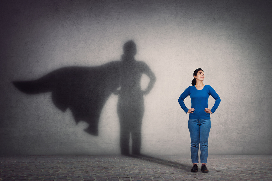 Woman standing with a shadow showing her having a cape - being a superhero