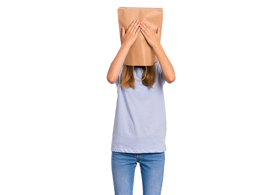 Person with long hair with a paper bag over their head. They are holding their hands over the paper bag where their eyes would be, accentuating their refusal to see.